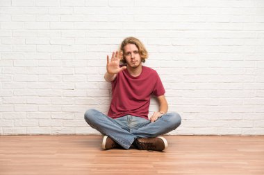 Yerde oturan sarışın adam stop jest yapma