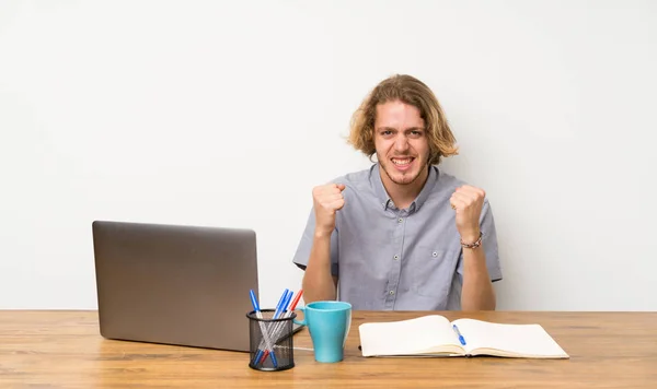 Blonde man with a laptop celebrating a victory in winner position