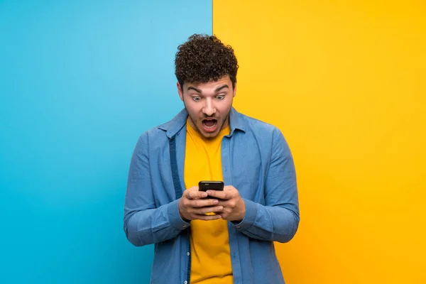 Man Curly Hair Colorful Wall Surprised Sending Message — Stock Photo, Image