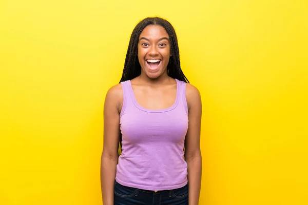 非洲裔美国少女与长辫子的头发在孤立的黄色墙壁与惊喜的面部表情 — 图库照片