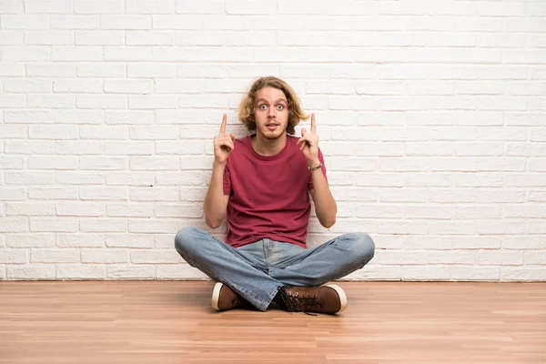 Blonder Mann Sitzt Auf Dem Boden Und Zeigt Eine Großartige — Stockfoto