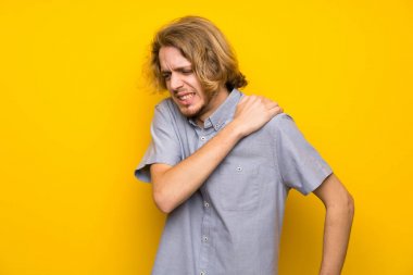 Bir çaba yapılmış için omuz ağrısı muzdarip izole sarı arka plan üzerinde sarışın adam