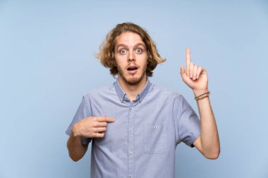 Sarışın adam sürpriz yüz ifadesi ile izole mavi duvarın üzerinden
