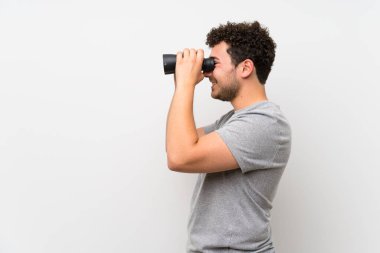 Siyah dürbün ile izole duvar üzerinde kıvırcık saçlı adam