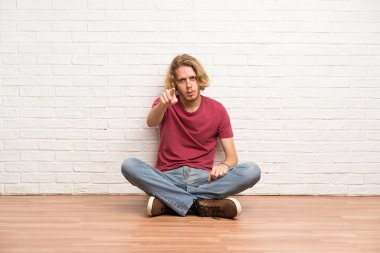 Sarışın adam yerde oturan sürpriz ve ön işaret