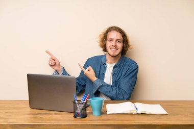 Yan parmak işaret eden bir laptop ile sarışın adam