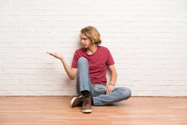 Yerde oturan sarışın adam şüpheleri ile boşaltmak tutarak