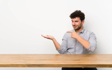 Bir reklam eklemek için avuç üzerinde taklit alanı hayali tutan bir tablo ile genç adam