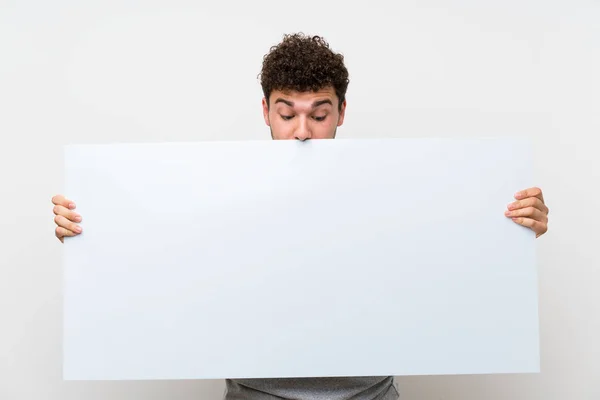 一个卷曲的头发在隔离的墙上拿着一个空的白色标语牌 插入一个概念的人 — 图库照片