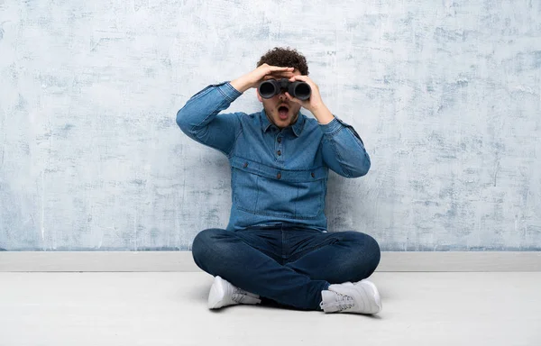 Jonge Man Zittend Vloer Met Zwarte Verrekijker — Stockfoto