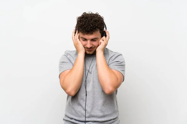 Człowiek Kręconymi Włosami Izolowanej Ścianie Słuchanie Muzyki Słuchawkami — Zdjęcie stockowe