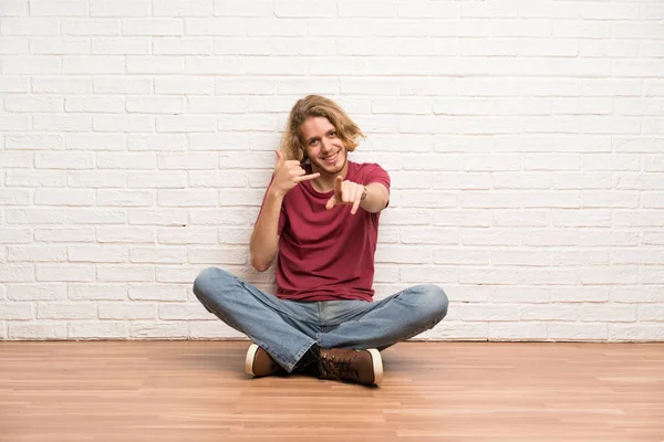 Uomo Biondo Seduto Sul Pavimento Che Gesto Del Telefono Punta — Foto Stock