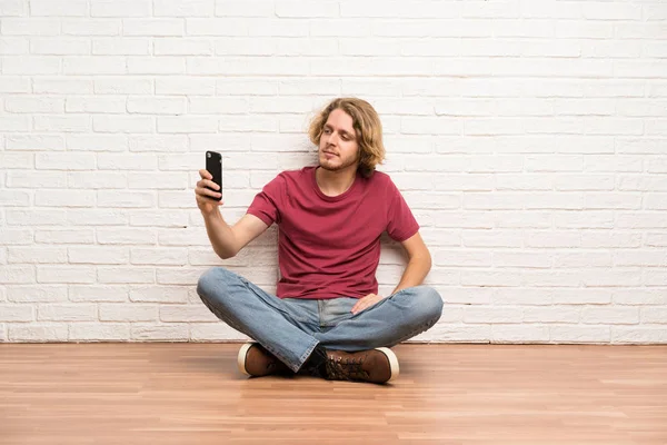 Ξανθός Άνθρωπος Κάθεται Στο Πάτωμα Φτιάχνοντας Μια Selfie — Φωτογραφία Αρχείου