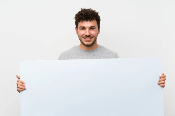 Człowiek Kręconymi Włosami Nad Izolowaną Ścianą Posiadając Pusty Biały Afisz — Zdjęcie stockowe
