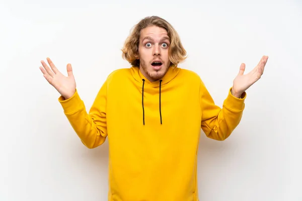 Blond Man Med Sweatshirt Över Vit Vägg Med Chockad Ansiktsuttryck — Stockfoto