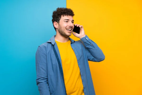 Renkli Duvar Üzerinde Kıvırcık Saçlı Adam Cep Telefonu Ile Bir — Stok fotoğraf