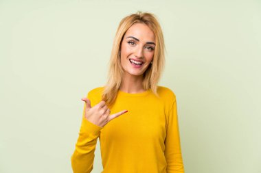 İzole yeşil arka plan üzerinde genç sarışın kadın telefon jest yapma