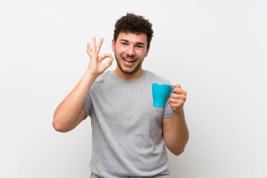 Sıcak bir fincan kahve tutan izole duvar üzerinde kıvırcık saçlı adam