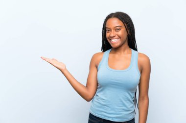 Uzun örgülü saç ile Afrika Amerikan Genç kız izole mavi arka plan tutan kopya hayali üzerinde palmiye