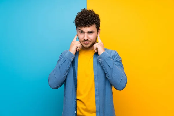 Homem Com Cabelo Encaracolado Sobre Parede Colorida Frustrado Cobrindo Orelhas — Fotografia de Stock