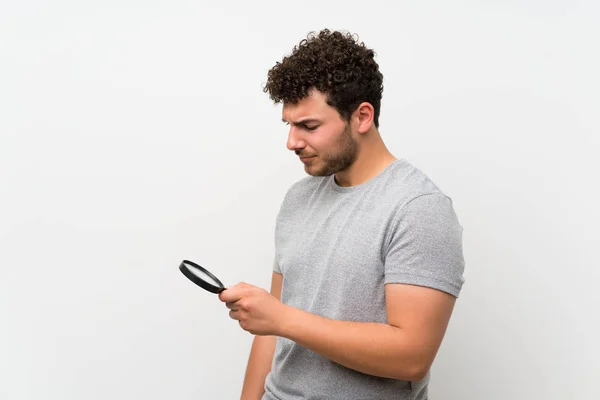 Homem Com Cabelo Encaracolado Sobre Parede Isolada Segurando Uma Lupa — Fotografia de Stock