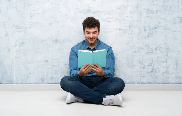 Ung Man Sitter Golvet Hålla Och Läsa Bok — Stockfoto