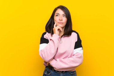 Izole sarı arka plan üzerinde genç Meksikalı kadın bir fikir düşünme
