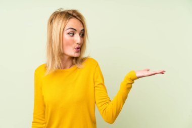 Küçük sarışın kadın üzerinde izole yeşil arka plan tutan boşaltmak hayali üzerinde palmiye