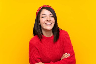 Sarı duvar üzerinde kırmızı kazak ile genç Meksikalı kadın gülüyor
