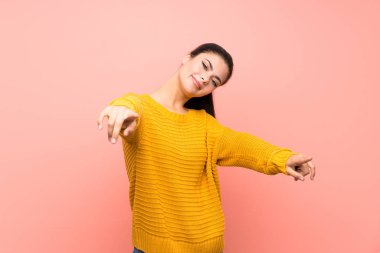 Genç kız üzerinde izole pembe duvar noktaları parmak üzerinde gülümserken