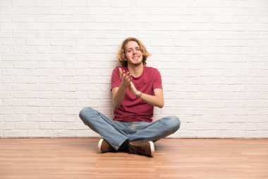 Bir konferansta sunum sonrası alkışlamak yerde oturan sarışın adam