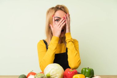 Gözleri kapsayan ve parmaklarla bakarak sebze Lots ile genç sarışın kadın