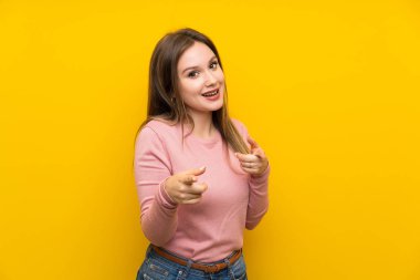 Genç kız üzerinde izole sarı arka plan puan parmak size