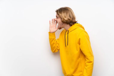 Beyaz duvar üzerinde Sweatshirt ile sarışın adam ağız geniş açık yanak ile bağırıyor