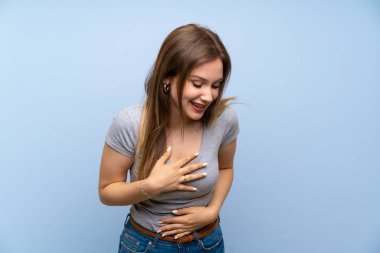 Genç kız üzerinde izole mavi duvar çok gülümseyen