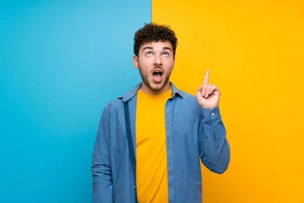 Uomo Con Capelli Ricci Sopra Parete Colorata Che Punta Verso — Foto Stock