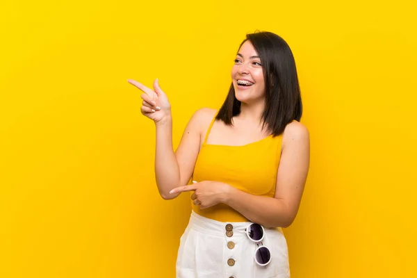 Молода Мексиканська Жінка Над Ізольованим Жовтим Фоном Вказуючи Пальцем Збоку — стокове фото