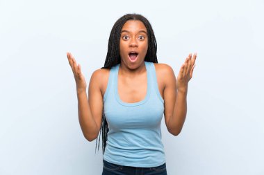 Şaşırtıcı yüz ifade ile izole mavi arka plan üzerinde uzun örgülü saç ile Afrikalı Amerikan Genç kız