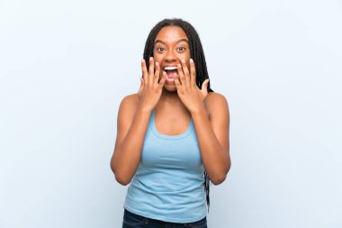 Şaşırtıcı yüz ifade ile izole mavi arka plan üzerinde uzun örgülü saç ile Afrikalı Amerikan Genç kız