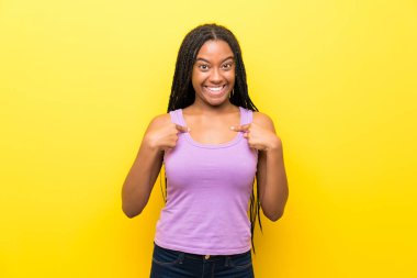 African American teenager girl with long braided hair over isolated yellow wall with surprise facial expression clipart