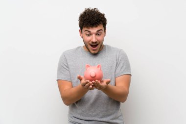 Büyük bir kumbara tutan izole duvar üzerinde kıvırcık saçlı adam