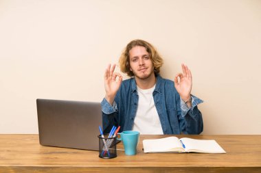 Parmaklar ile bir ok işareti gösteren bir laptop ile sarışın adam