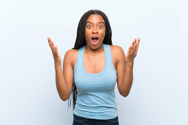 African American teenager girl with long braided hair over isolated blue background with surprise facial expression