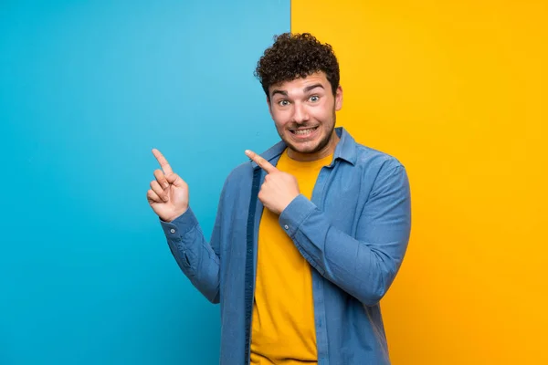 Homem Com Cabelo Encaracolado Sobre Parede Colorida Assustado Apontando Para — Fotografia de Stock