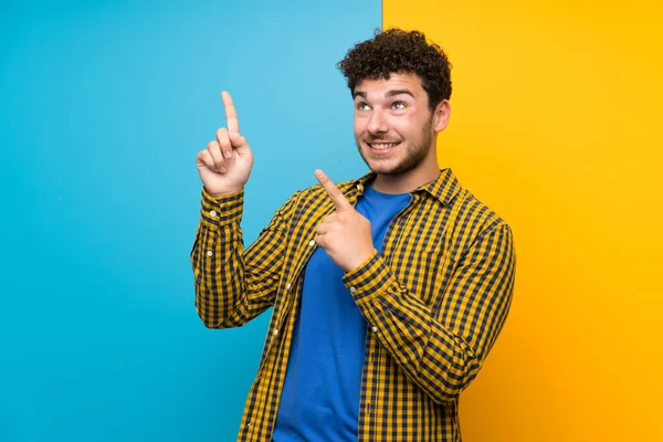 Man Med Lockigt Hår Över Färgglada Väggen Pekar Med Pekfingret — Stockfoto