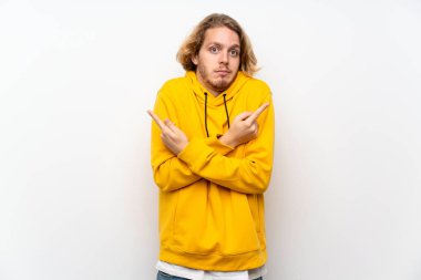 Beyaz duvar üzerine Sweatshirt ile sarışın adam şüpheleri olan lateraller işaret