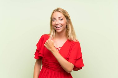 Bir zaferi kutlayan izole yeşil arka plan üzerinde Sarışın genç kadın