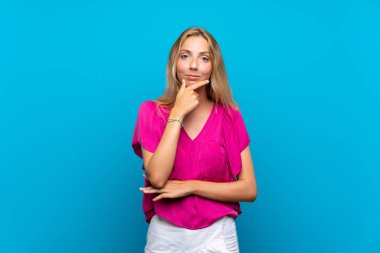 Izole mavi arka plan düşünme üzerinde Sarışın genç kadın