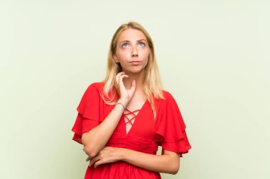 Izole yeşil arka plan üzerinde Sarışın genç kadın bir fikir düşünme