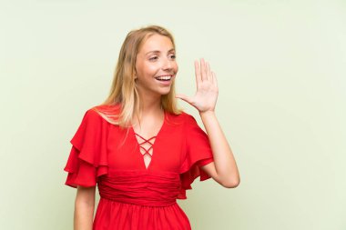 Ağzı tamamen açık bağırarak izole yeşil arka plan üzerinde Sarışın genç kadın